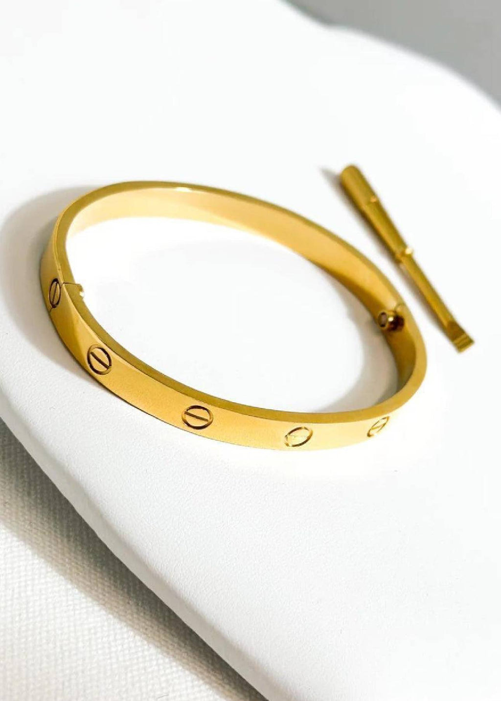 Gold bracelet with heart-shaped cutouts on a white surface