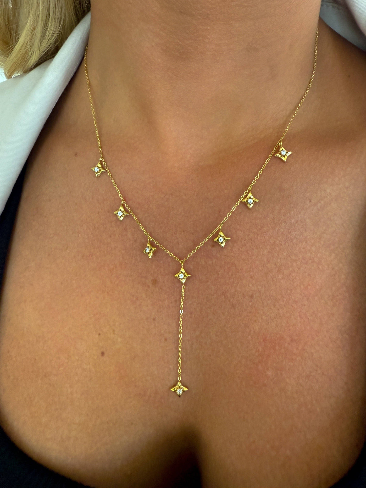 Gold necklace with floral pendants on a person's neck